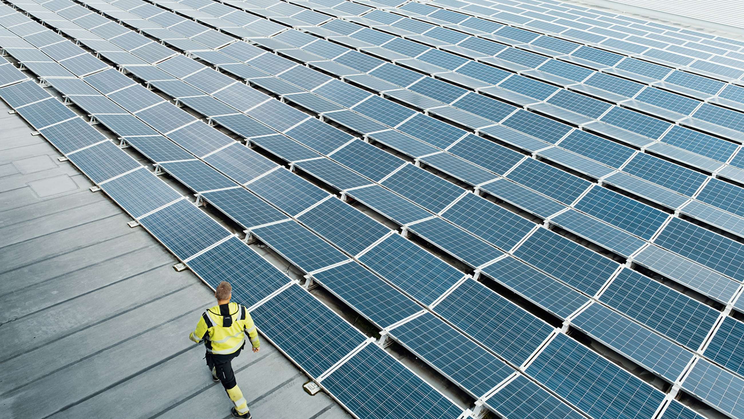 Mannlig medarbeider går på taket på en terminal ved siden av en rekke solceller.