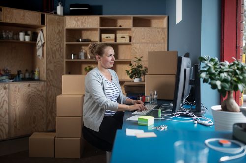 Dame foran en PC ved et arbeidsbord med esker