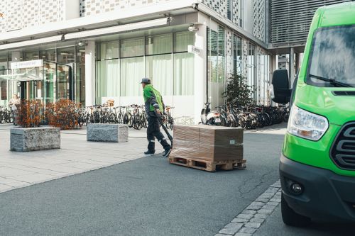 Mannlig Bring-bud leverer en pall med varer til en bedrift