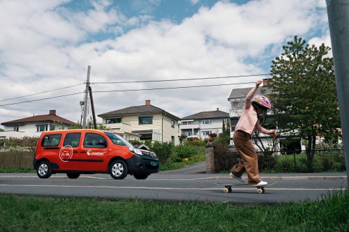 Child on a skateboard, Posten vehicle in the background