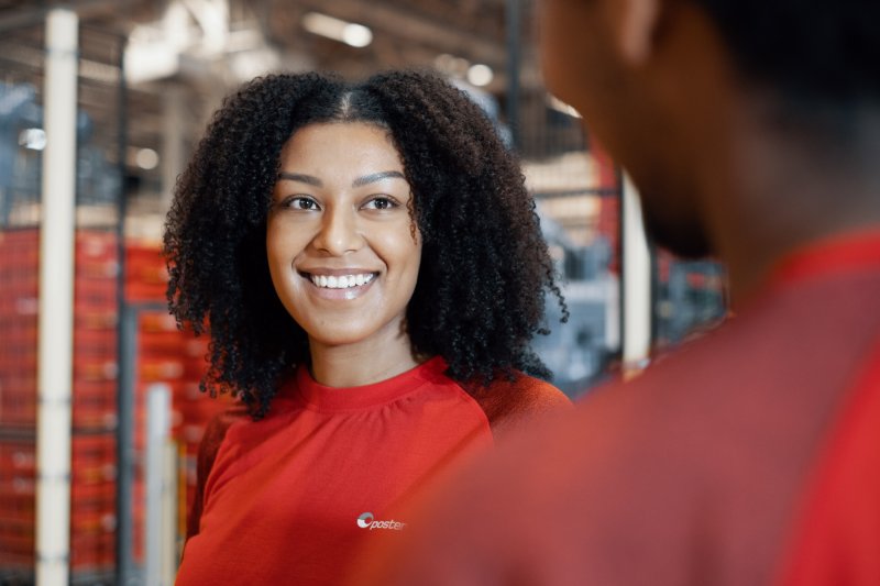 Posten-ansatt smiler til kollega
