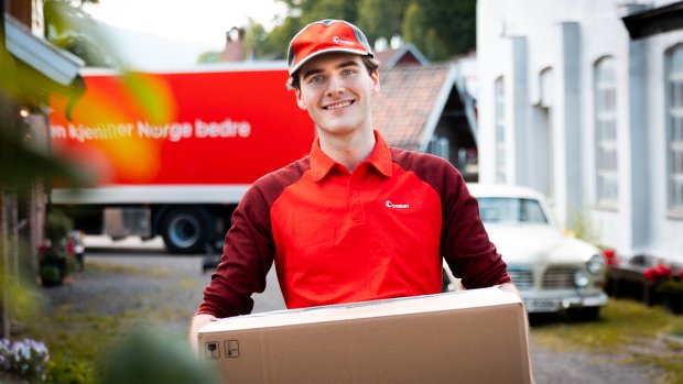 Smilende yrkessjåfør fra Posten holder en pakke