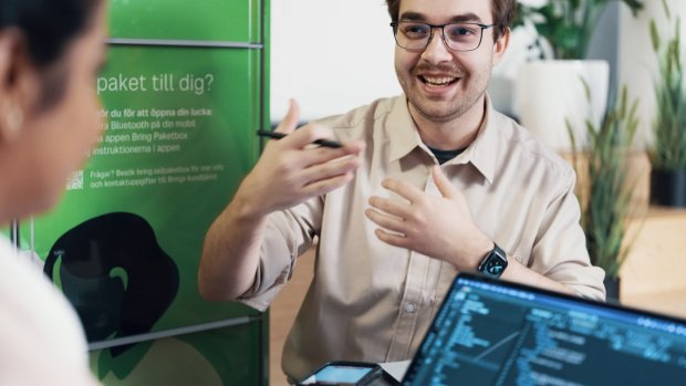 To ansatte i Posten Bring i hyggelig prat foran en pakkepoks fra Bring Sverige
